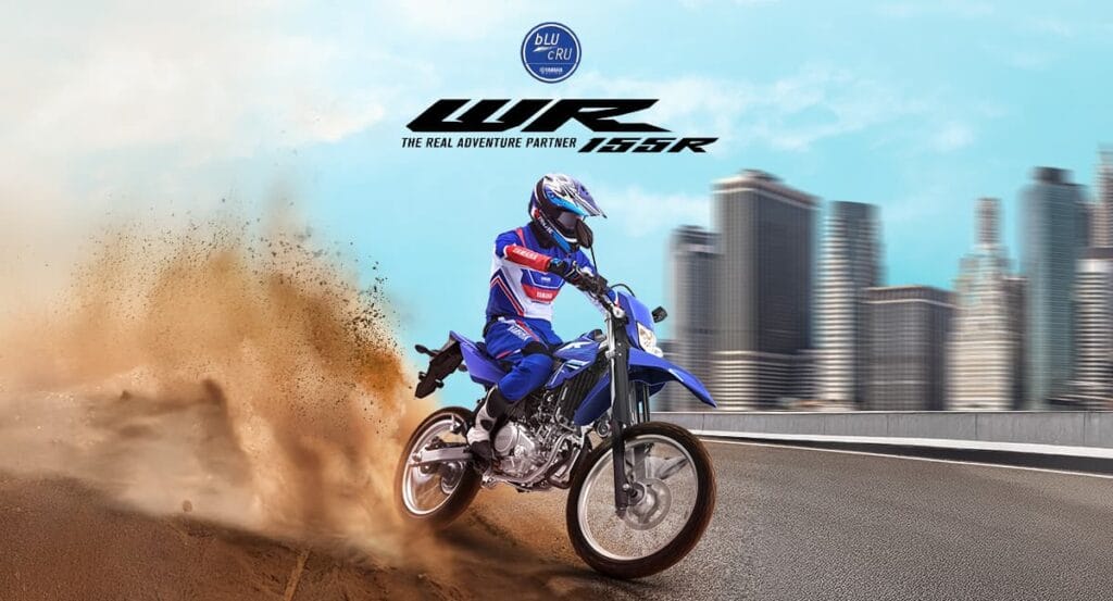 Motor yamaha wr 155 berwarna biru berlatar diantara perkotaan dan rally